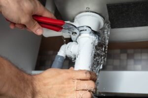 Plumber fixing leaking sink pipe with wrench