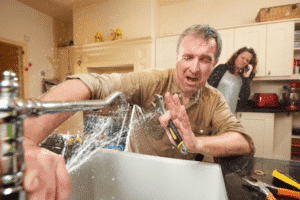 Man repairing leaking kitchen sink with spraying water